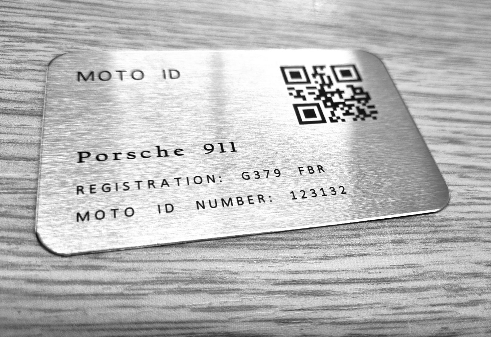 A Moto ID plate laser-marked with a Porsche 911's registration and Moto ID number, next to its QR code
